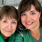Two women with brown hair, one older one younger, embrace and smile at the camera.