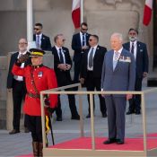 Officer in Red Serge offers salute next to King Charles III standing on a pedestal.