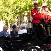 Two Mounties ride coach as King Charles, Queen Camilla and two others ride in an open carriage.