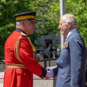 A high-ranking officer in Red Serge shakes hands with King Charles III.