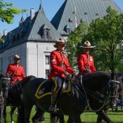 Mounties in saddle ride their horses in front of the Supreme Court of Canada.