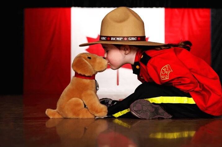 A child in Red Serge kisses a plush puppy