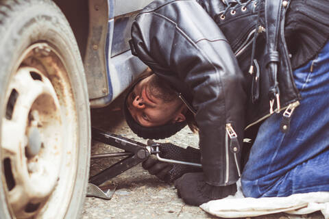Man staring underneath a car